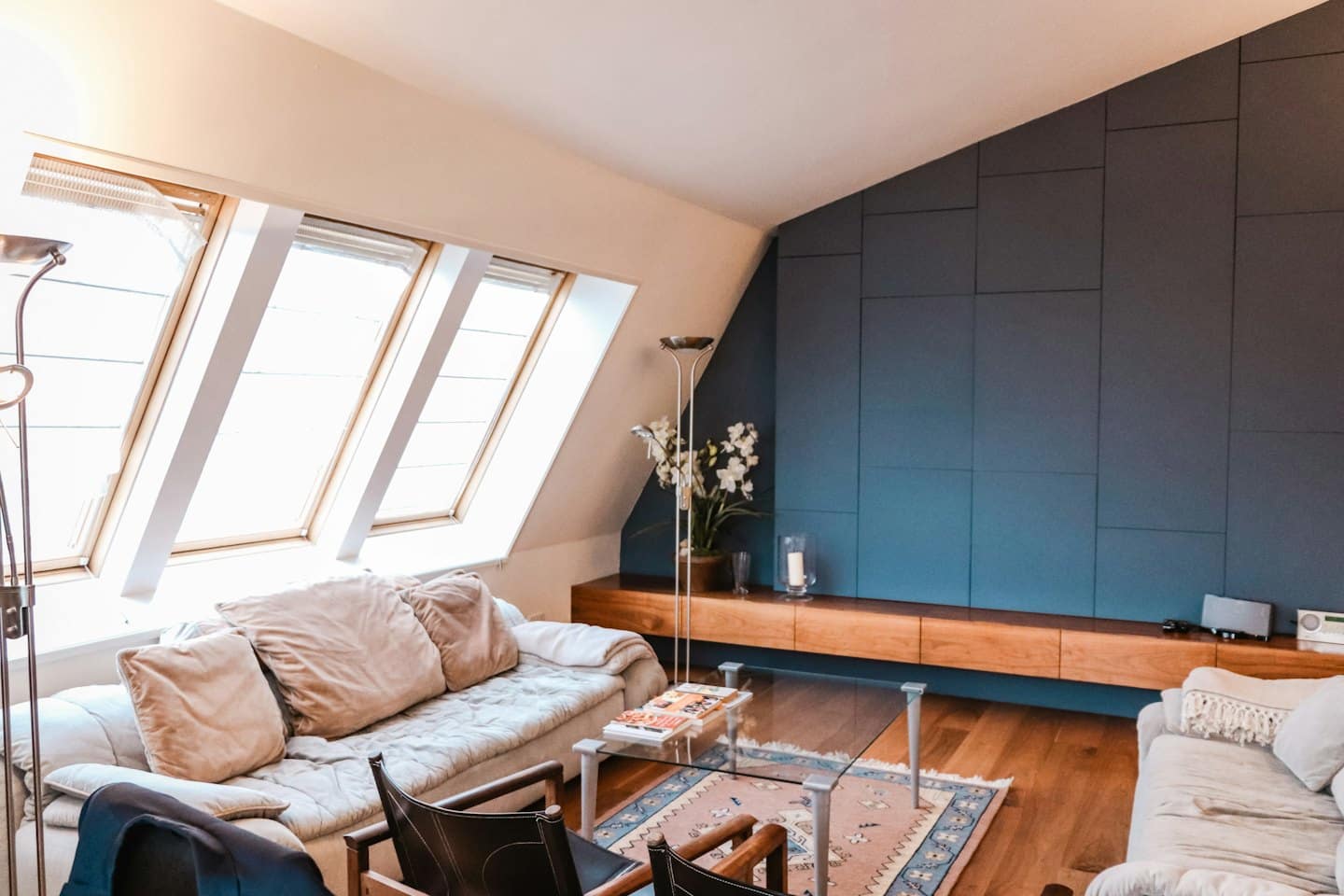 Modernes Wohnzimmer mit blauer Akzentwand und Dachfenstern.